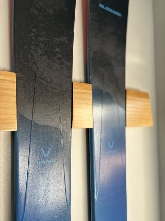Close up of blue skis mounted on Adventure Mounts Vert Chaser wood ski mount showing the intricate wood details and finish.
